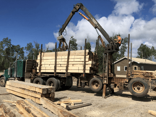 Sawmill machine loading large cut-wood onto transport