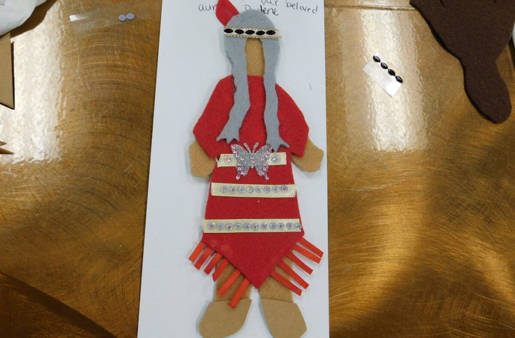 felt doll with a red ribbon dress and a feathered bandana