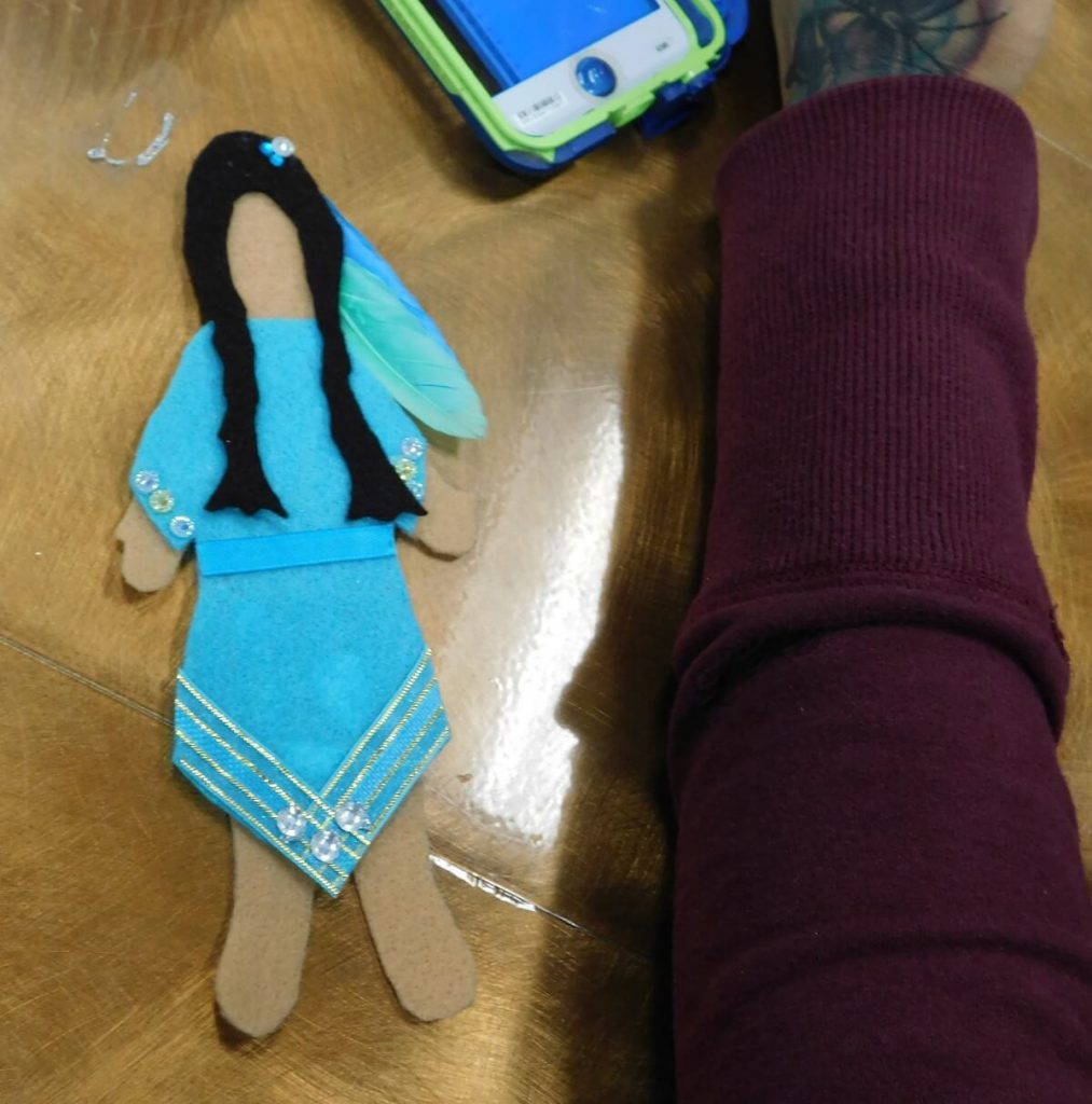 felt doll wearing blue dress and blue feathers in hair